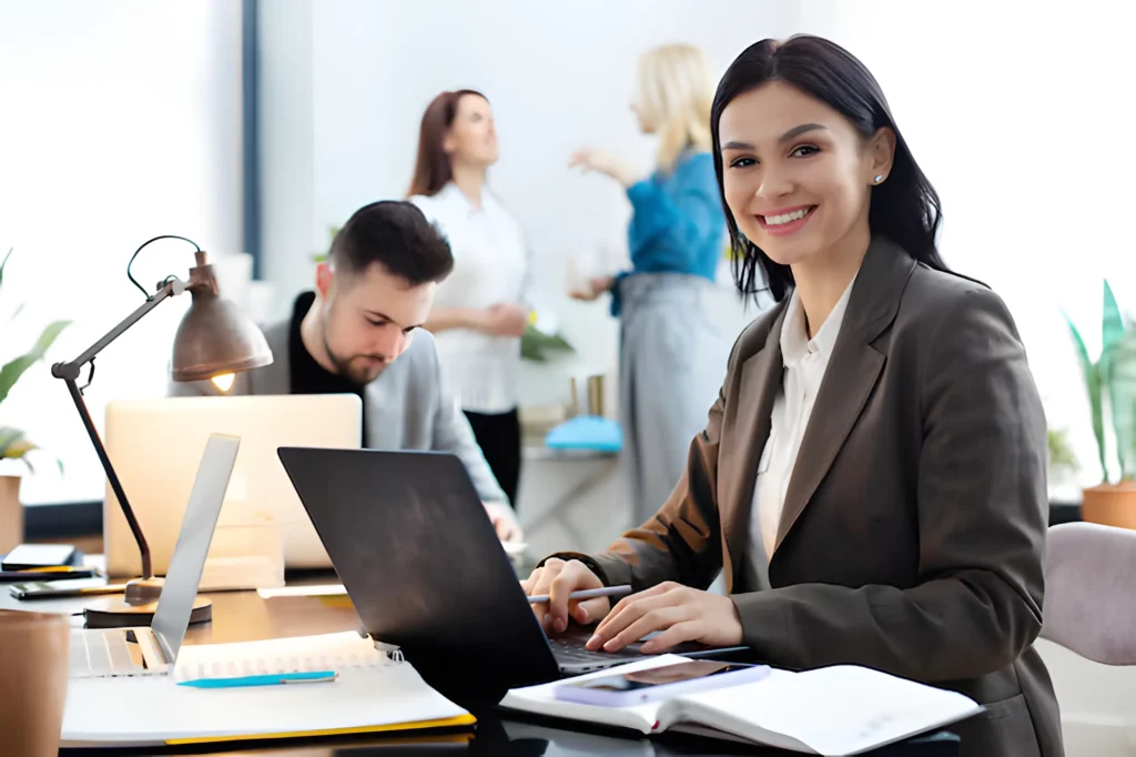 Smiling businesswoman typing on laptop in bright office