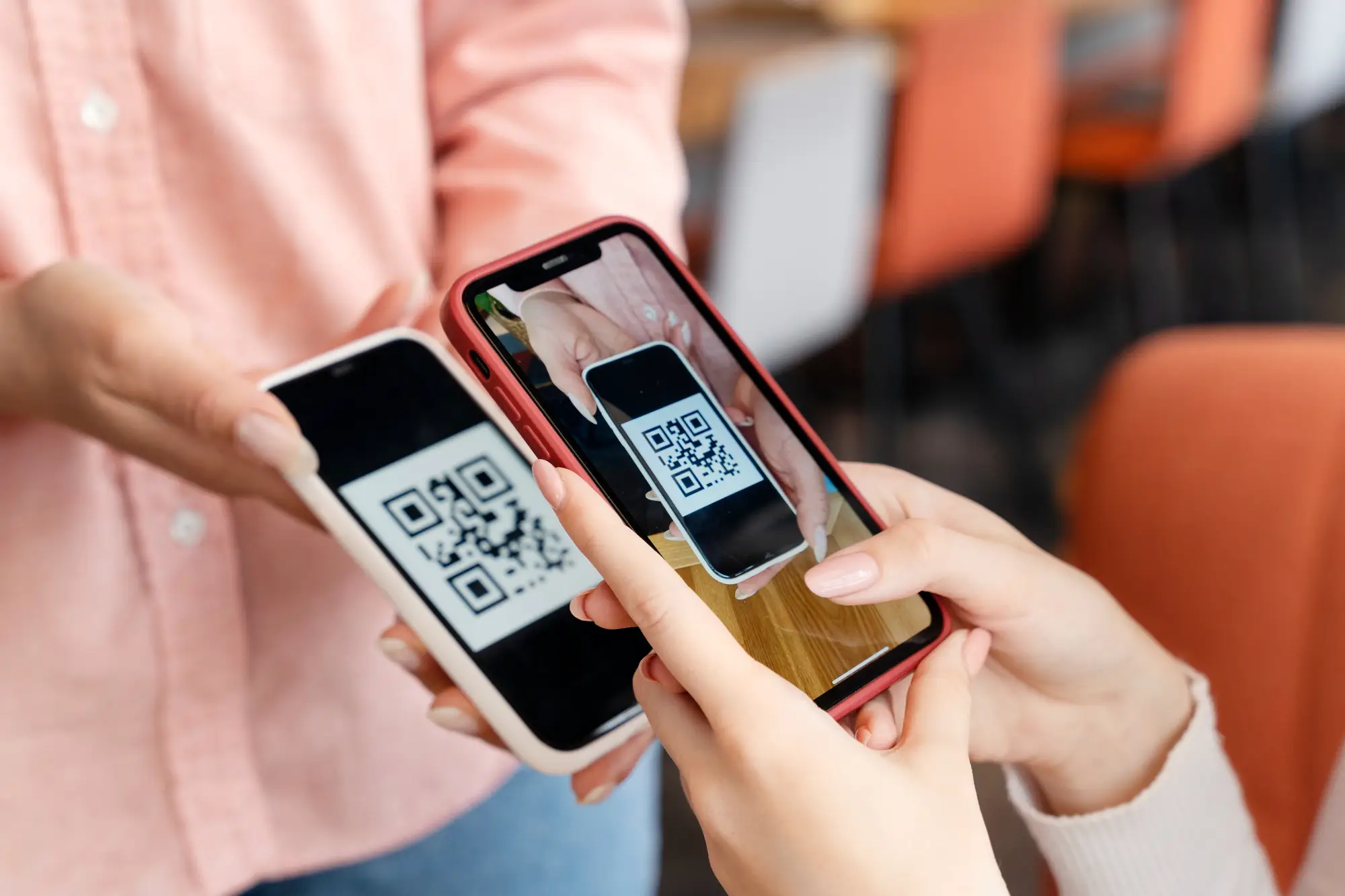 Two people scanning QR codes with smartphones for payment