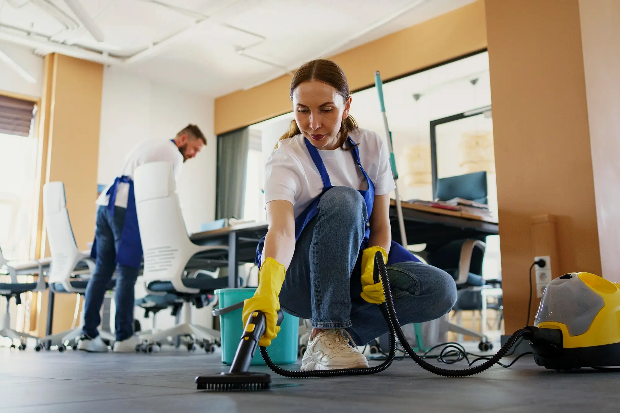 Woman steam cleaning office floor with portable cleaner machine