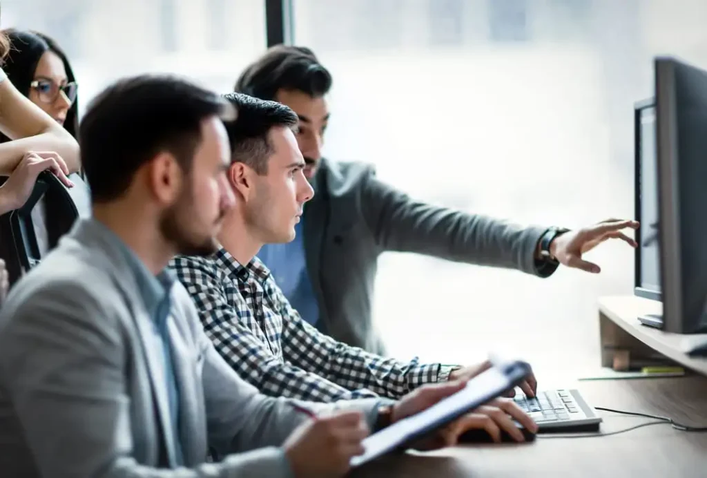 Business team collaborating and pointing at desktop monitor