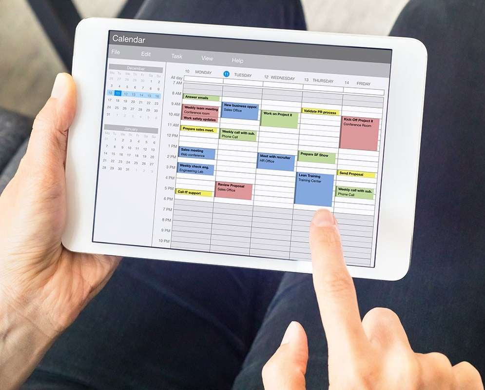 Hands holding tablet showing weekly calendar schedule