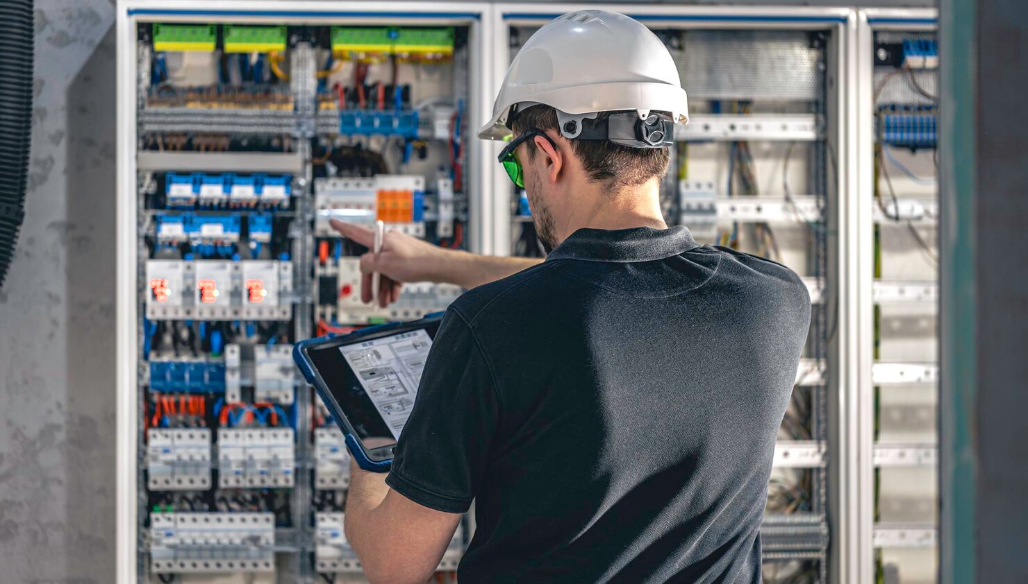 Electrician inspecting electrical control panel using tablet device